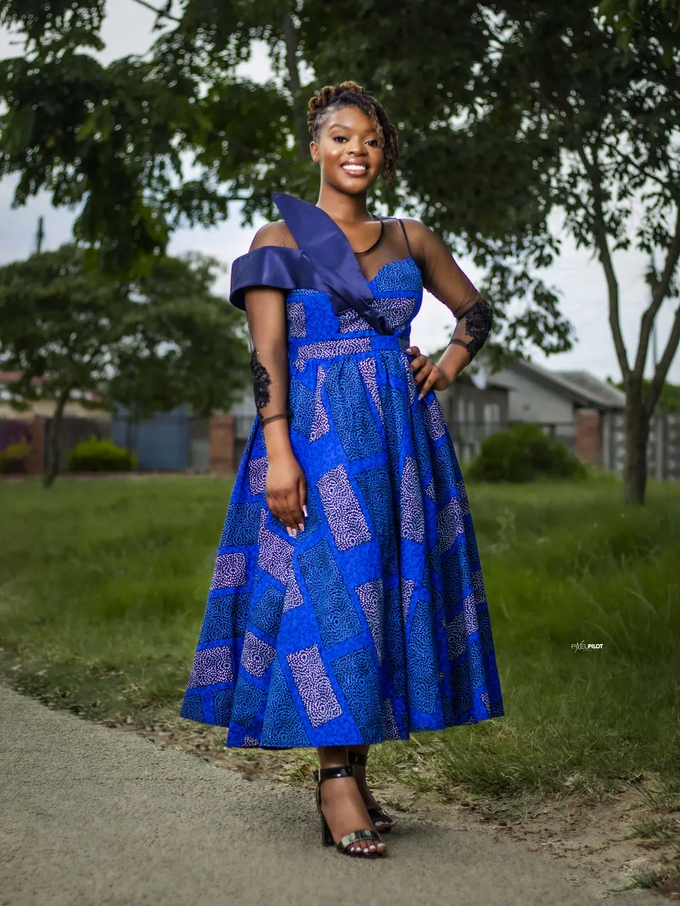 Woman in a blue African-print dress posing outdoors
