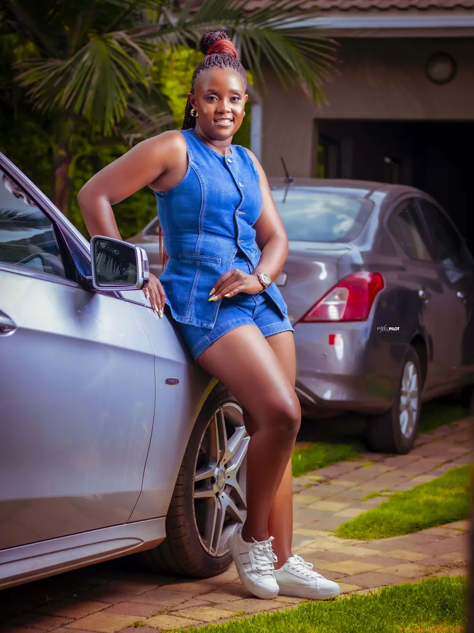 Woman in a denim set posing beside a silver Mercedes