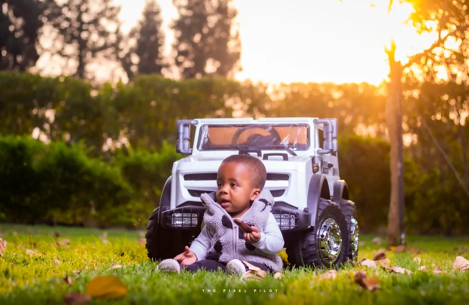 Toddler with a white toy jeep in golden-hour light