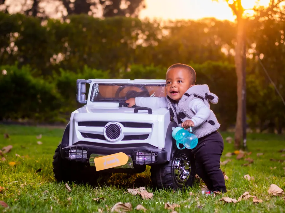 Toddler beside a white toy jeep at golden hour